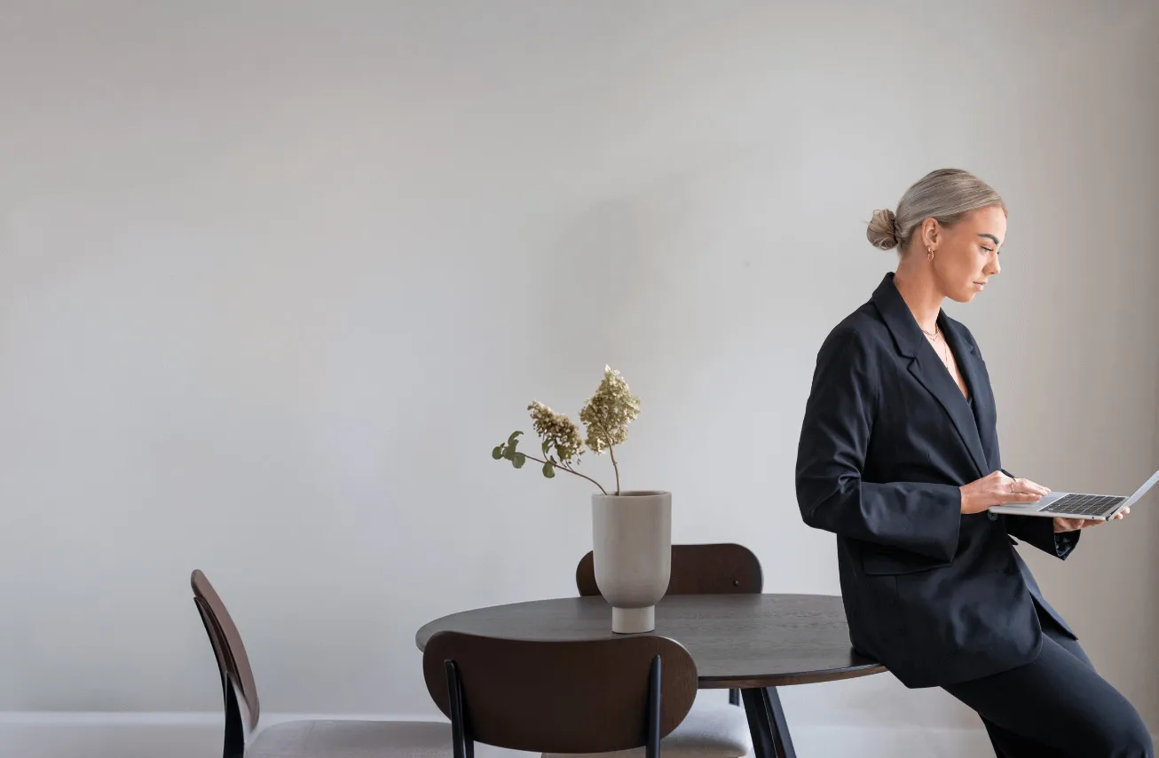 Eline War van E-warketing werkt op haar laptop, leunend tegen een tafel