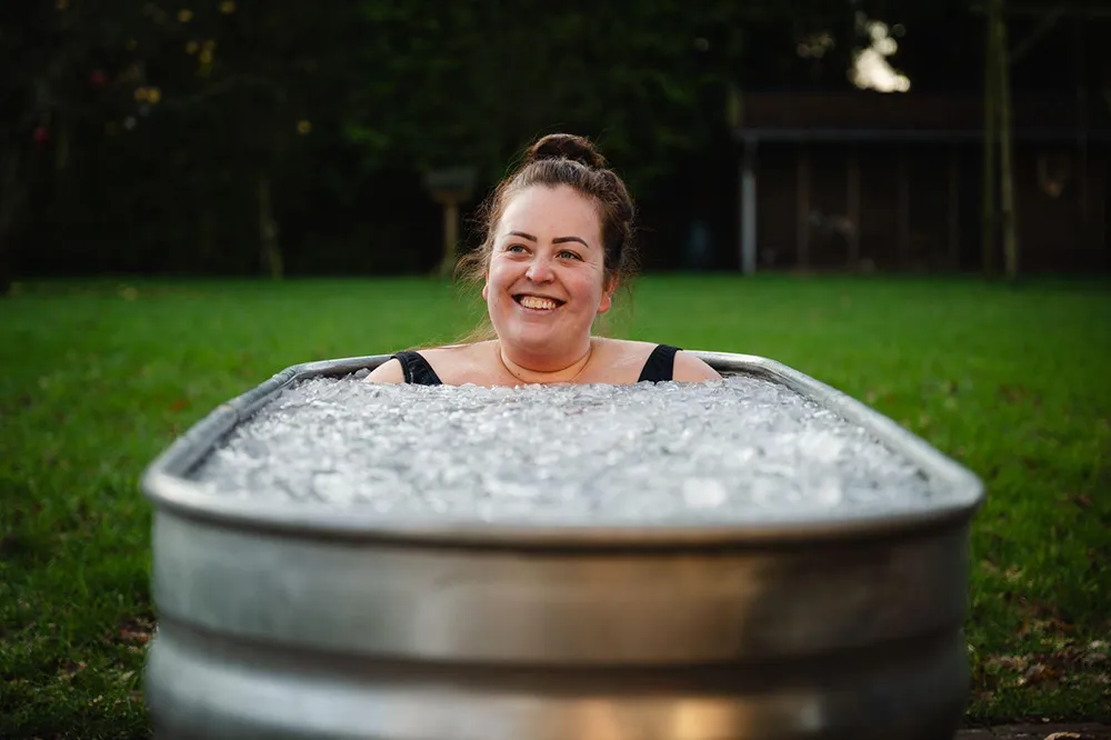 Een lachende deelnemer zit tot de schouders in een ijsbad
